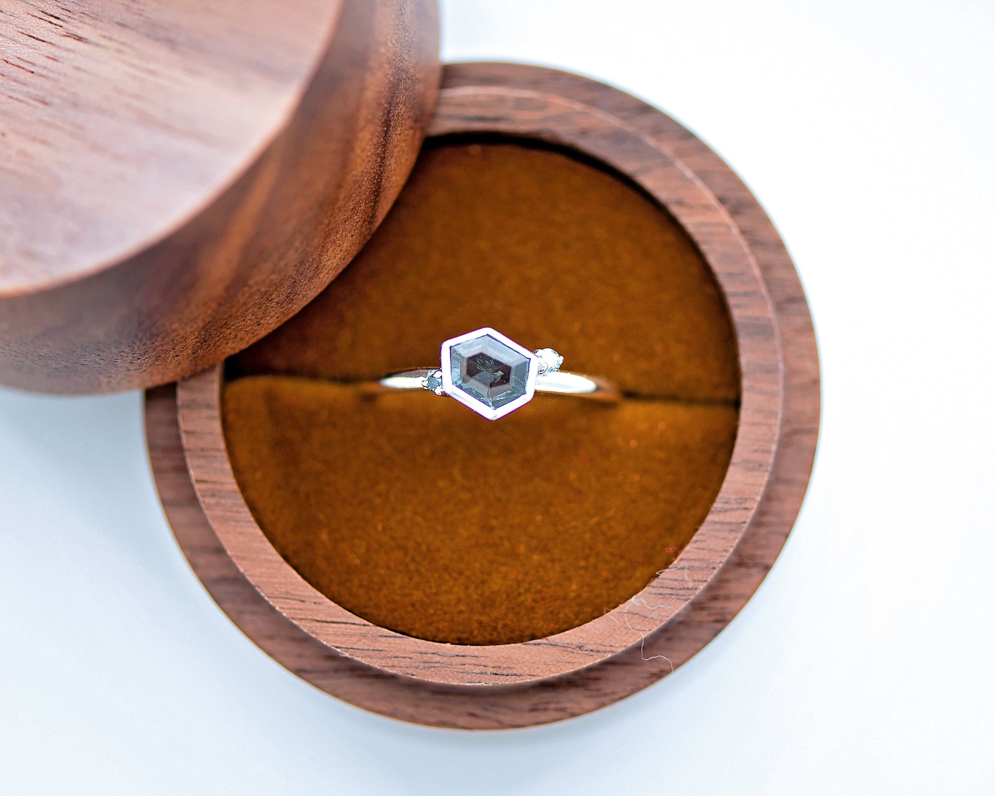Wooden ring box with a hexagonal gemstone ring on a white background