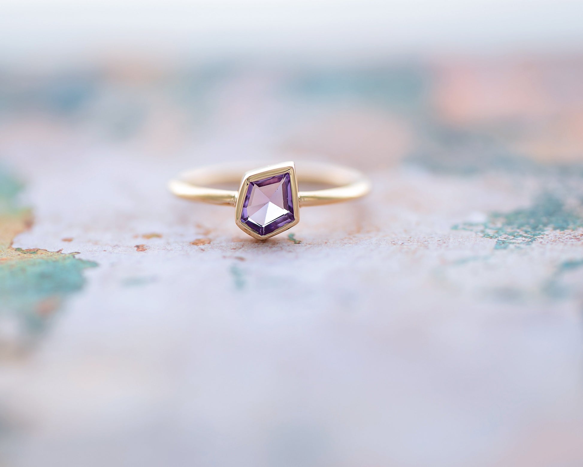 Gold ring with a purple gemstone on a blurred map background