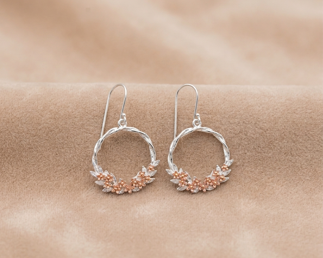 Silver hoop earrings with floral details on a beige background