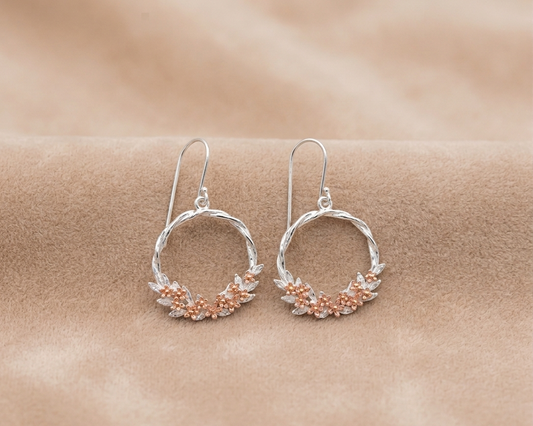 Silver hoop earrings with floral details on a beige background