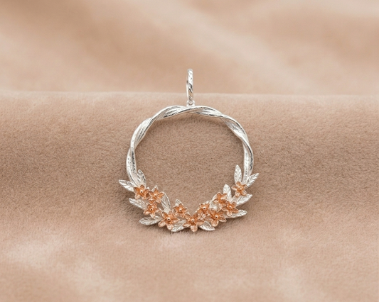 Silver pendant with floral designs on a beige background