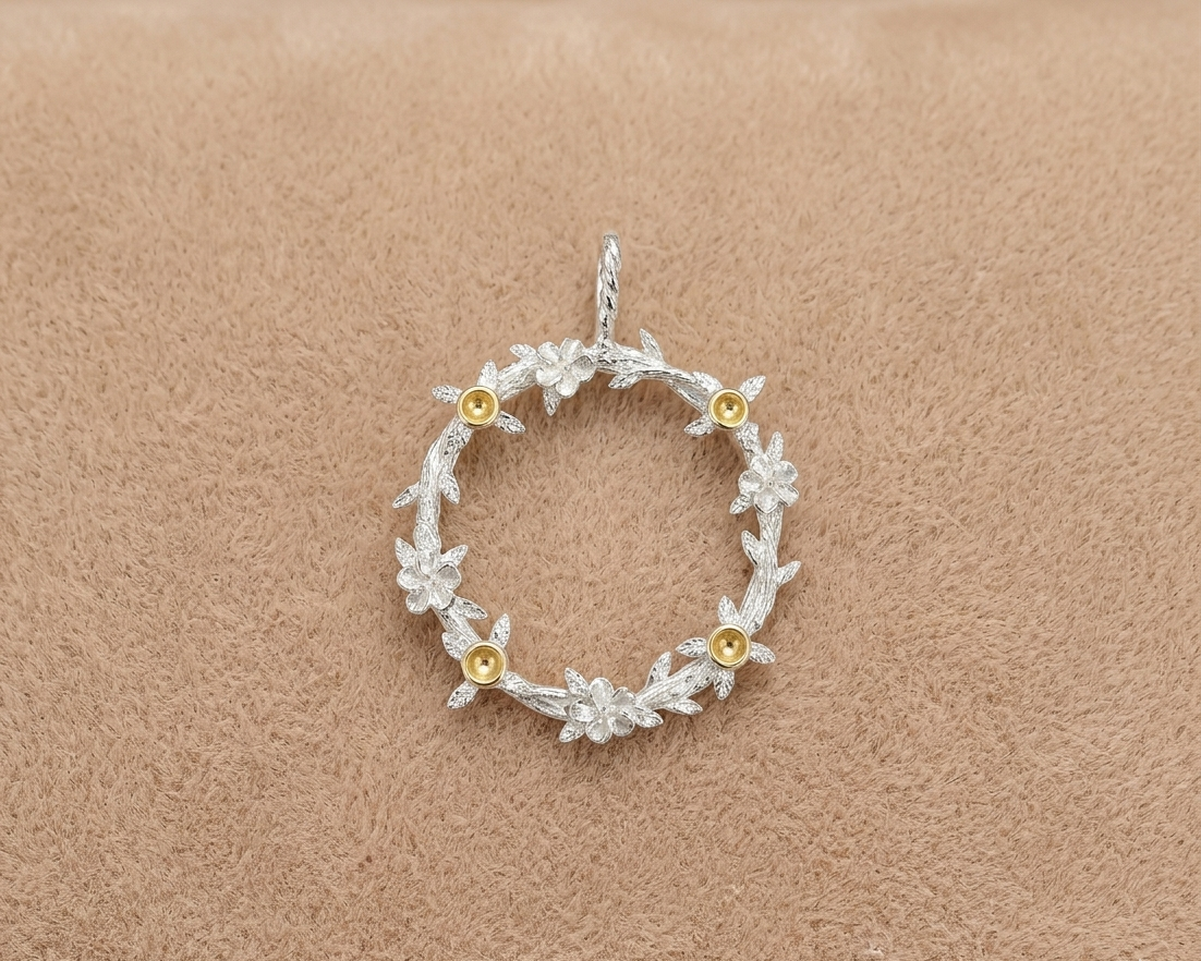 Silver floral pendant with gold accents on a beige background
