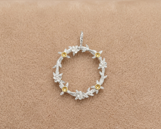 Silver floral pendant with gold accents on a beige background