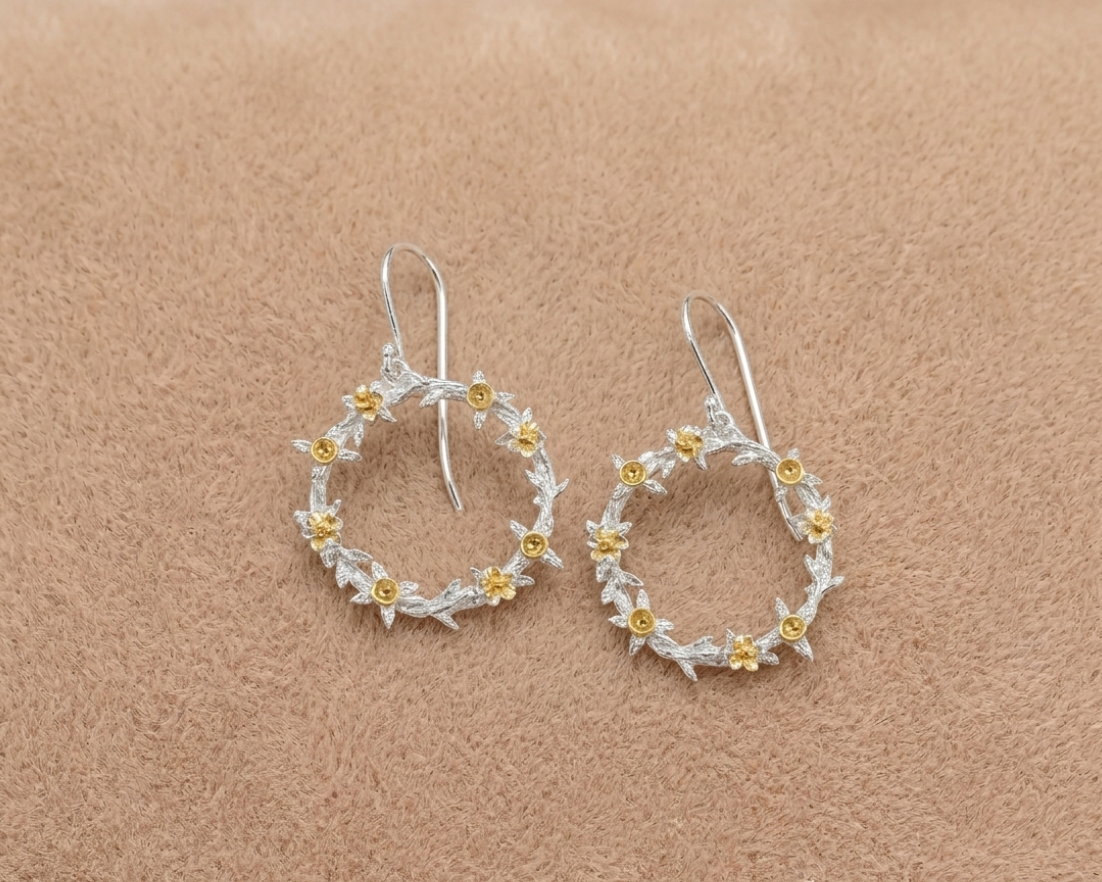 Pair of silver hoop earrings with gold accents on a beige background