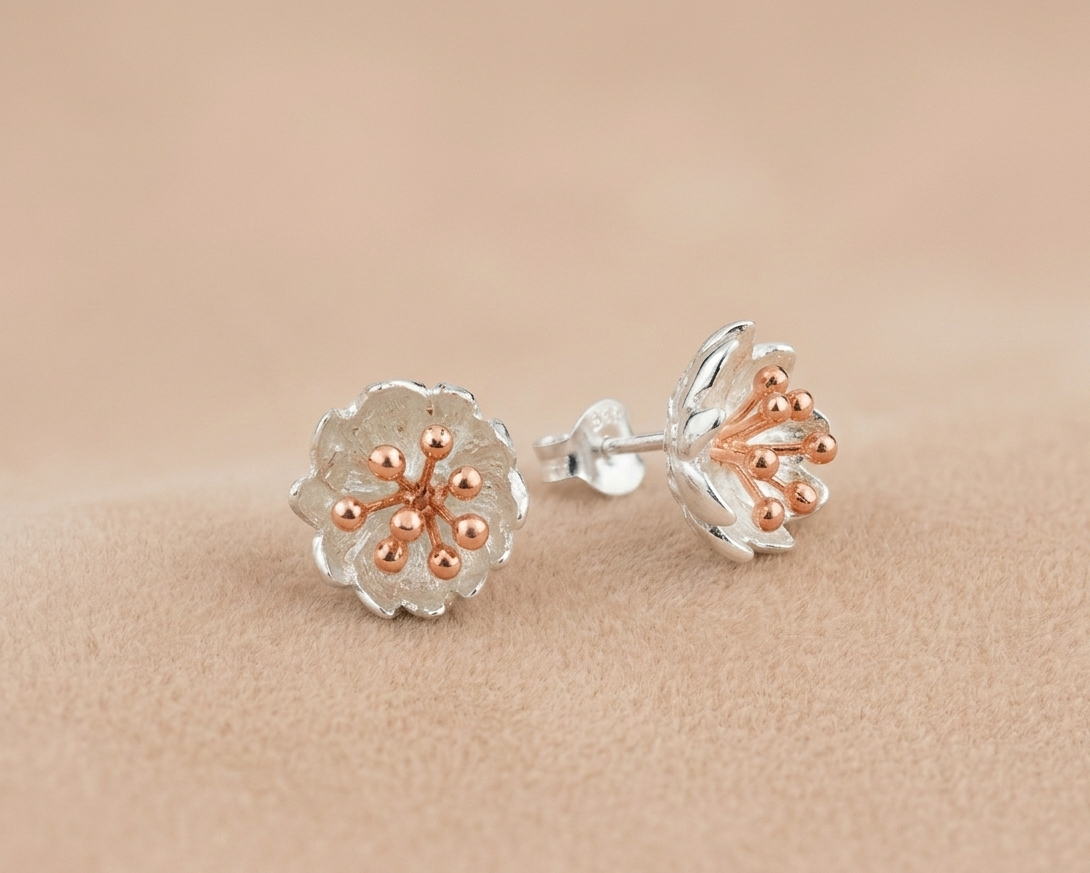 A contemporary sterling silver Calla Lily pendant featuring a delicate rose gold plated spadix resting on warm-toned velvet.