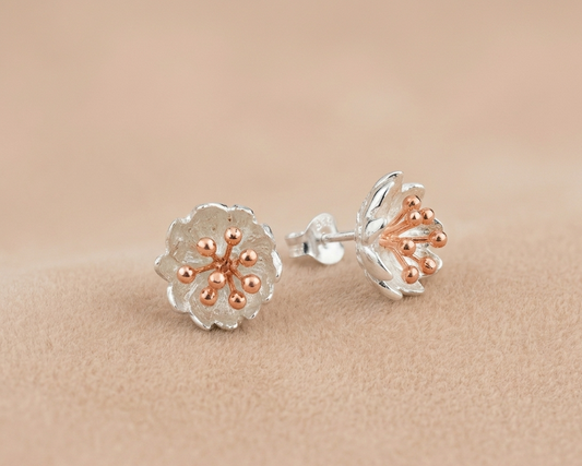 A contemporary sterling silver Calla Lily pendant featuring a delicate rose gold plated spadix resting on warm-toned velvet.