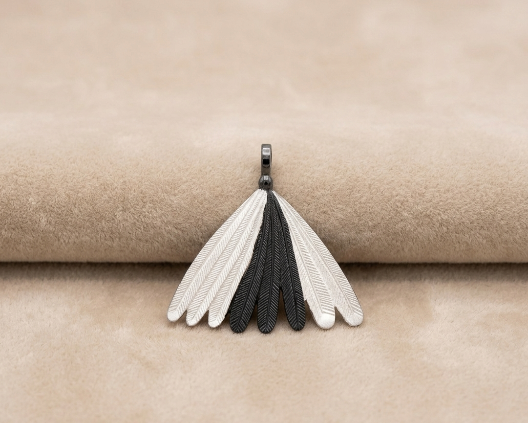 A sterling silver pendant featuring a fan of detailed Piwakawaka (Fantail) feathers with a contrasting oxidised finish on the central feathers displayed on soft skin-tone velvet.