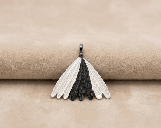 A sterling silver pendant featuring a fan of detailed Piwakawaka (Fantail) feathers with a contrasting oxidised finish on the central feathers displayed on soft skin-tone velvet.